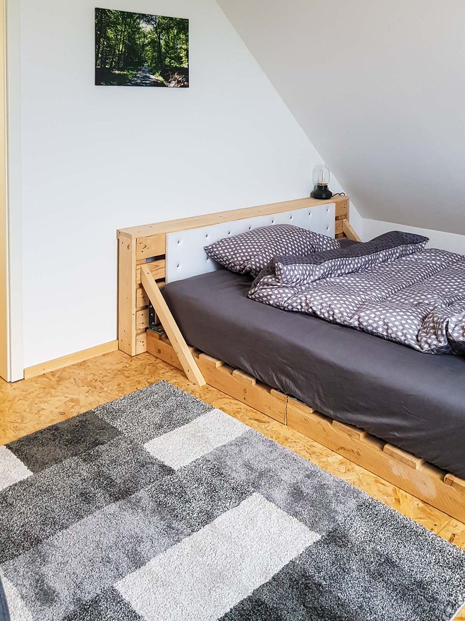 Schlafzimmer unter der Dachschräge mit Doppelbett und gemustertem Teppich