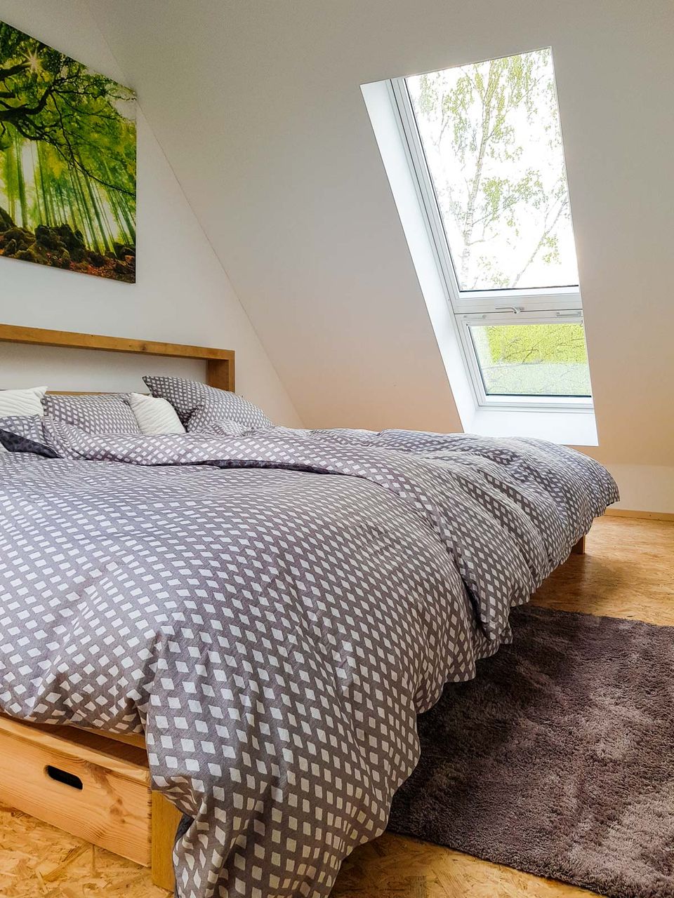 Doppelbett unter dem Dachfenster mit Blick ins Grüne