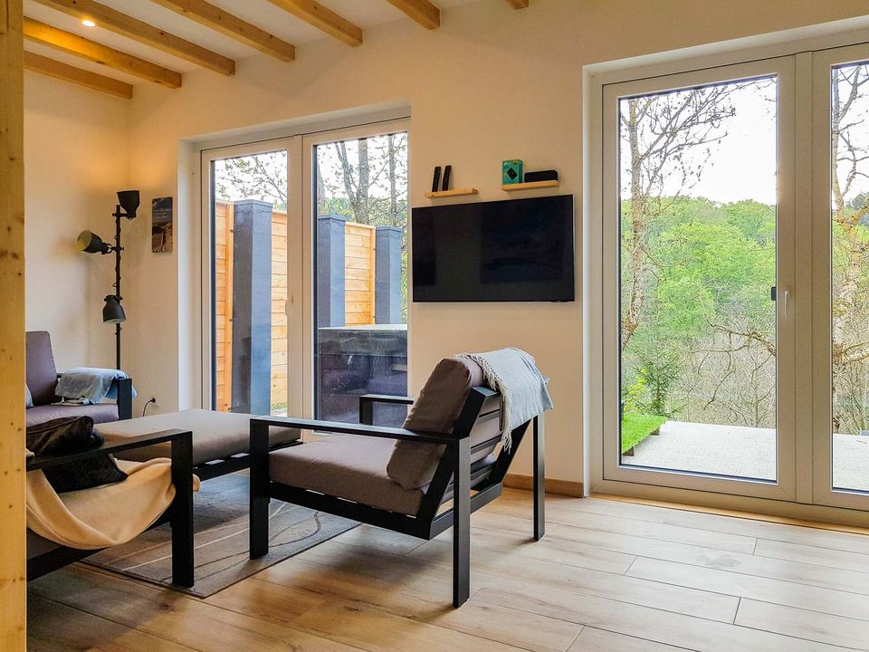 Wohnbereich mit Sesseln, Smart-TV und bodentiefen Fenstern zur Terrasse