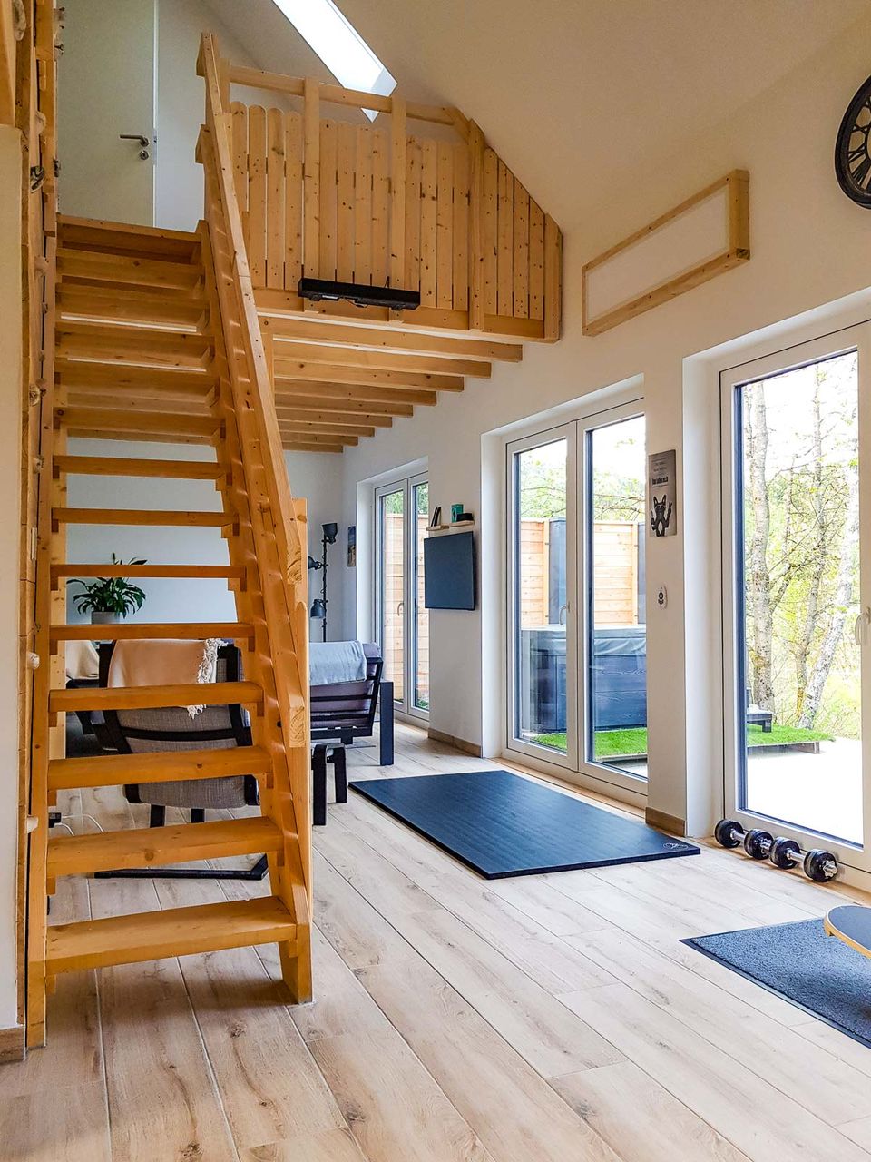 Offener Wohnraum mit Holztreppe zur Galerie und hoher Decke