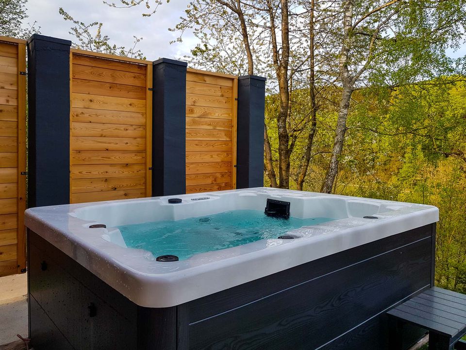 Beheizter Außenwhirlpool auf der Terrasse, dahinter ein Sichtschutz aus Holz