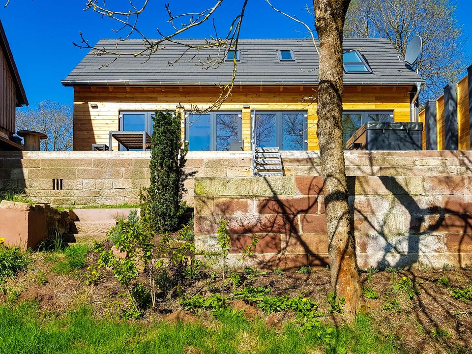 Das Ferienhaus von der Wiese aus gesehen, im Vordergrund eine alte Sandsteinmauer