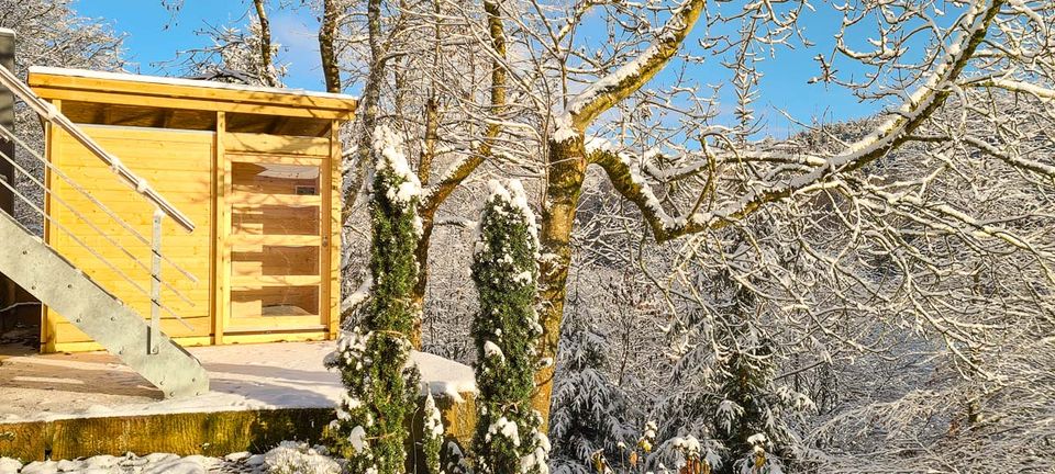 Holzverkleideter Außenbereich des Chalets unter schneebedeckten Bäumen